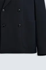 Blazer straight fit confeccionada en tejido de lana de origen italiano. Cuello con solapas de pico y manga larga acabada en puño con botones. Bolsillos de plastrón en pecho y cadera. Detalle de bolsillo interior. Bajo con aberturas en espalda. Cierre frontal de botonadura cruzada.