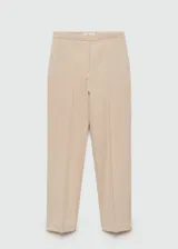 Pantalón de vestir color beige, de corte recto, con bolsillos laterales y traseros. Se ajusta a la cintura con cinturón de cuero marrón.