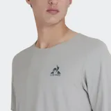Remera deportiva Le Coq Sportif Training Pro, color gris claro, de manga corta y cuello redondo. Presenta paneles laterales en gris oscuro y el logo de la marca bordado en el pecho.