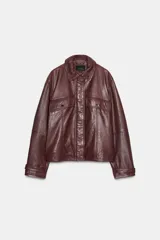 Cazadora marrón de cuero con cuello solapa y manga larga con trabillas. Tiene bolsillos de vivo y con solapa en delantero, detalle de costuras marcadas y cierre frontal con cremallera y botón a presión ocultos por sopata.