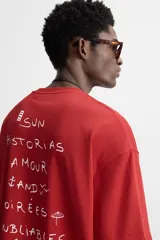 Camiseta roja de corte relajado, cuello redondo y manga corta. Estampado con texto en el frente y la espalda.
