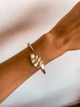 Brazalete con diseño de hoja en acabado metálico, adaptándose cómodamente a la muñeca.