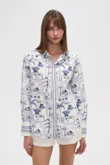 Camisa de manga larga con estampado de motivos playeros en tonos marrones sobre fondo beige, cuello camisero y cierre frontal con botones.