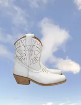 Botas cortas negras de cuero con bordados blancos estilo cowboy.