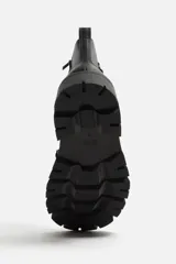 Bota de cuero negra con cordones, cordonera con nueve pasados, tirador trasero y suela track con volumen.