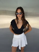 Mini pollera blanca de tela liviana con corte irregular y diseño con picos asimétricos.