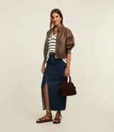 Falda midi de jean celeste con abertura delantera, trabillas en la cintura, cierre con botón y bolsillos.