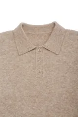 Suéter de punto suave color beige, con cuello polo y detalle de tres botones en la parte frontal. De manga larga y tejido abrigado.