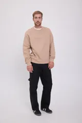 Buzo color beige de manga larga con cuello redondo y puños acanalados. Interior suave con acabado cepillado y estampado en relieve con efecto tridimensional.