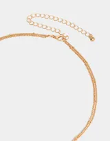 Collar corto dorado multicadena con dije ovalado celeste con estrellas y dijes de estrellas colgantes.