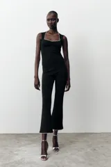 Pantalón negro de tiro alto, corte ajustado y cintura elástica. El ruedo es acampanado y está decorado con perlas.