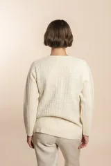 Cardigan tejido con efecto fantasia color crema. Una prenda de silueta amplia y cómoda. Tejido en 100% lana fina sin teñir.