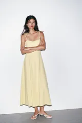 Vestido midi amarillo claro, con escote corazón con volantes y tirantes finos ajustables con lazo. Falda acampanada con forro interior.