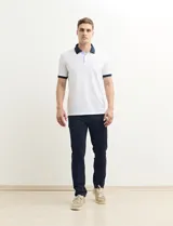 Remera polo blanca de piqué con cuello y puños en azul marino. Tiene tapeta de dos botones y bolsillo de parche en el pecho.