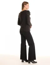 Buzo negro de tejido suave, marca Zac & Rachel, con cuello a la base y manga larga. Presenta hombros plisados y decorados con perlas.