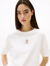 Remera blanca de corte relaxed con cuello redondo y logo Tommy Hilfiger gráfico estampado en el pecho.