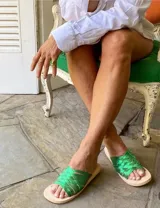 Sandalias chatas con tiras trenzadas de cuero metálico color verde.