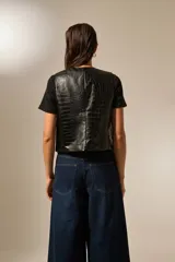Chaleco negro de eco-cuero con textura de cocodrilo, corte entallado y cierre frontal con botones metálicos.