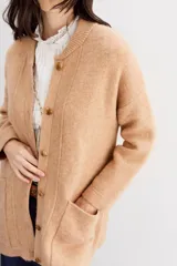 Tapado color beige de tejido de hilado suave y mullido, con calce relajado, mangas largas, cuello redondo y botones a tono.