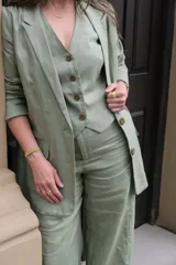 Blazer verde seco de lino, con corte entallado, solapas clásicas y cierre frontal con botones.
