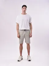 Bermuda color gris con cintura elástica ajustable con cordón, bolsillos laterales y un bolsillo tipo cargo en la pierna izquierda.