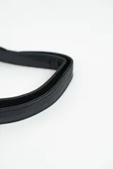 Riñonera negra de cuero sintético con correa ajustable y cierre superior con cremallera. Decorada con tachas plateadas en el borde inferior.