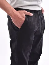 Pantalón jogger de denim azul con cintura elástica ajustable con cordón blanco, bolsillos laterales y puños elásticos.
