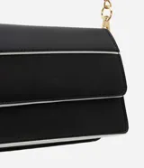 Cartera transversal pequeña de poliuretano negro con detalles en blanco y asa de cadena dorada.