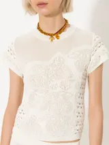 Top tejido en hilado frío color blanco, con puntos calados que generan textura. De manga corta y calce al cuerpo.