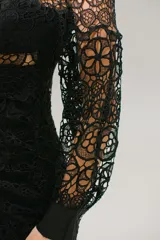 Vestido corto de encaje negro con escote en V, mangas largas abullonadas y falda con volados. Presenta cierre invisible en la espalda.