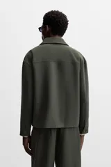 Sobrecamisa verde oscuro de corte cuadrado, con cuello solapa, manga larga con puños abotonados, bolsillos de parche en el pecho y bolsillos laterales en la cadera. Cierre frontal con botones.