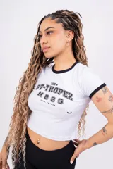 Remera corta de jersey color rosa con cuello redondo y mangas cortas con ribete blanco. Estampado frontal con la inscripción "ST-TROPEZ" en letras blancas.