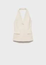 Chaleco color crema con cuello halter, espalda descubierta, botón joya, bolsillos delanteros y corte entallado.