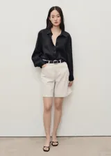 Shorts de tiro alto color crema con finas rayas verticales, trabillas para cinturón, cierre frontal con cremallera y botón, y cinco bolsillos.