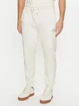 Pantalón de chándal color crema, con cintura elástica ajustable con cordón, puños de canalé, bolsillos laterales y trasero. Presenta el monograma de Calvin Klein bordado en la pierna.
