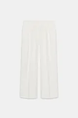 Pantalón blanco de tiro alto con bolsillos delanteros y falsos bolsillos traseros con tapeta. Detalle de pliegues en delantero. Cierre frontal con cremallera y gancho metálico.