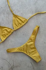 Conjunto de bikini verde esmeralda, con corpiño triangular de atar al cuello y espalda, con almohadillas desmontables, y bombacha colaless con laterales fijos.