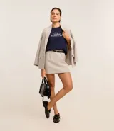 Short pollera de sastrería confeccionado en polivelour color beige. Tiene trabillas en la cintura, cierre por cremallera delantero, recorte en V en la parte trasera de la cintura, pliegues y pinzas delanteras. Incluye cinturón fino de material sintético con hebilla.