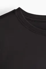 Remera deportiva negra de corte holgado, cuello redondo y mangas cortas. Confeccionada en tejido funcional DryMove™ que ayuda a absorber el sudor.