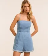 Enterito corto de jeans celeste, con breteles finos, escote cuadrado, lazo en la espalda y ruedo doblado.