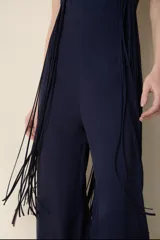 Mono largo color celeste, con escote halter cruzado, corte ajustado en la cintura y detalle de flecos largos en los laterales.