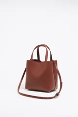 Bolso tote pequeño de cuero sintético color negro con doble asa de mano y correa bandolera ajustable y extraíble. Logotipo de la marca en letras doradas en la parte frontal.