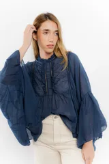 Camisa blanca de mangas largas con puntillas y cuello mao.