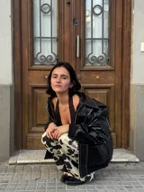 Chaqueta negra de cuero sintético con costuras blancas en contraste, cuello clásico y cierre frontal con botones a presión.