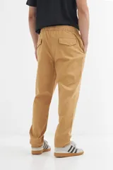 Pantalón de gabardina color ocre, con corte recto, cintura elastizada con cordón ajustable y bolsillos laterales.