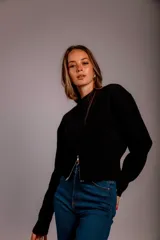 Buzo gris de punto con cuello redondo, mangas largas abullonadas y cierre frontal asimétrico.