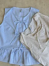 Blusa sin mangas con estampado de cuadros vichy celeste y blanco, con escote en V y lazos decorativos.