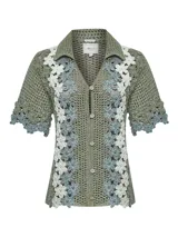 Chaleco de crochet color verde con detalles florales en blanco y celeste, con cuello camisero y cierre frontal con botones.