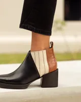 Botines Chelsea de cuero, color negro, con detalles en cuero marrón texturizado (tipo cocodrilo) y paneles laterales en color beige claro. Tienen un taco ancho y cuadrado, y cierre de cremallera lateral en color beige.