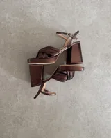 Sandalia de cuero vacuno color dorado, con plataforma y taco cuadrado. Presenta una tira delgada en el tobillo y detalle de nudo en la capellada.